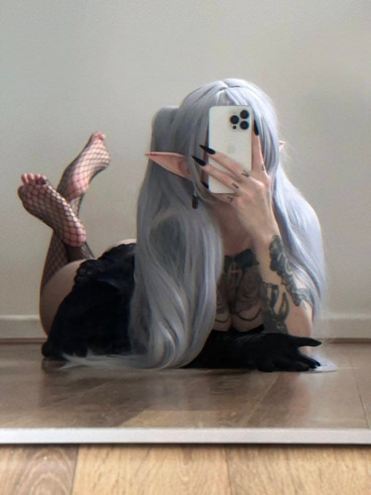 Woman in elf cosplay with long silver hair and pointed ears lying on the floor