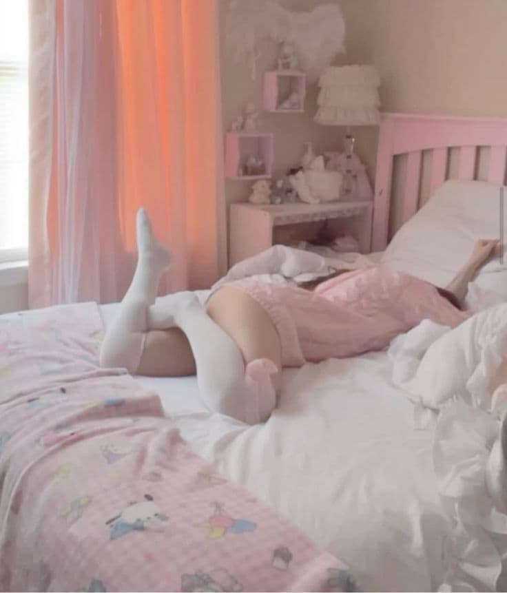 Girl in pink outfit and white knee-high socks lying on pastel bed reading a book